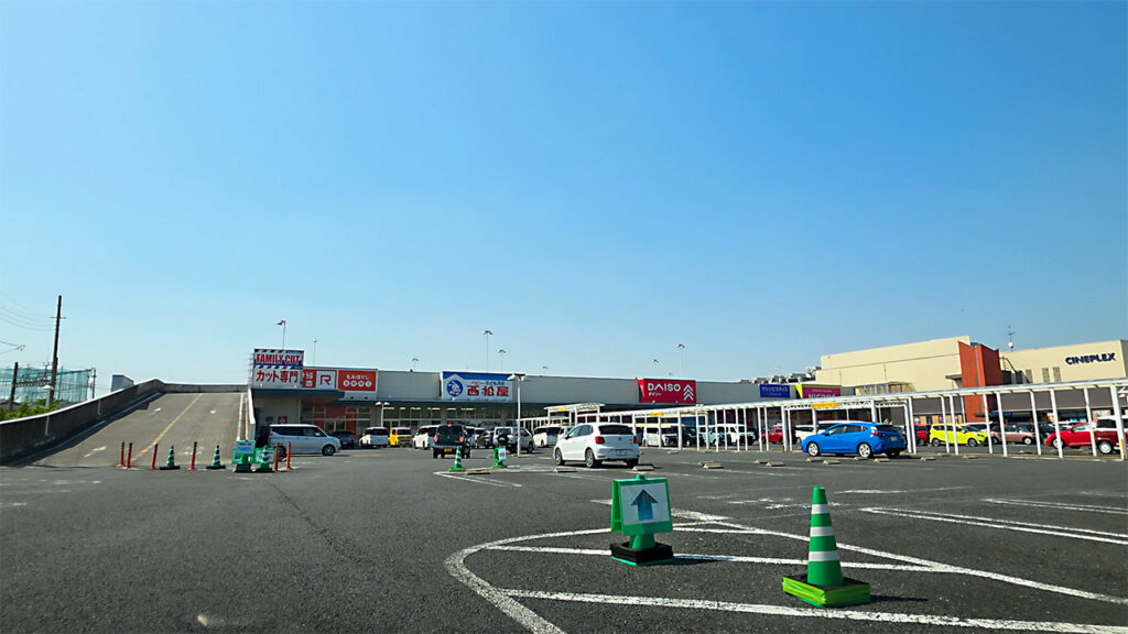 エムズタウン幸手 第2駐車場入口付近から平面駐車場と店舗方面が見える様子
