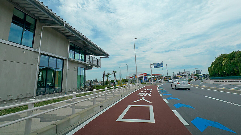 道の駅 湘南ちがさきの建物と屋外平面駐車場入口のP案内が見える道路